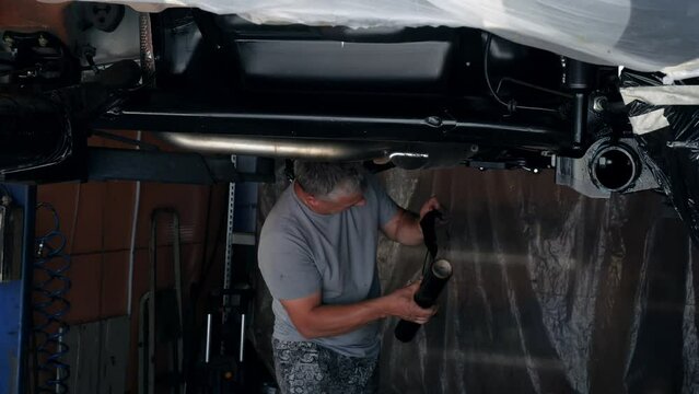 A worker wraps the elements of the bottom of the car with stretch film.