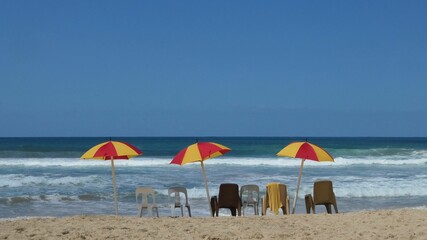 Fototapeta na wymiar beach with umbrella and chairs against blue sky