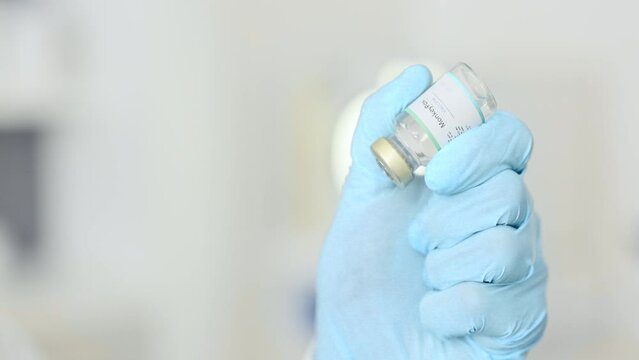 Doctor filling a syringe with a vaccine at a clinic to cure a patient. A scientist in the COVID 19 medical research and development laboratory holds an injection needle with liquid antibiotics