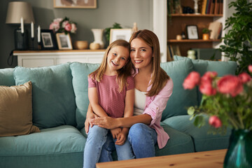 Portrait of embraced mother and daughter in the living room