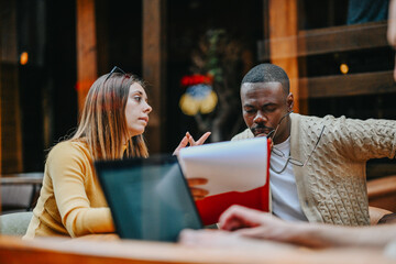 Young, multiracial executives meets at a coffee bar to discuss market research, sales growth, and marketing campaign for projects with target group trends focusing on scalability.