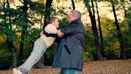 Dad plays with her child, spins her joyful son. Happy family, baby. Child, son runs to his Father, hugs her in autumn park, Twirl kid round. Carefree child happily hugs his Father. Father spins child