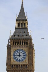 Portrait view of Big Ben with an airplane flying by, located in London
