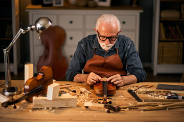 Senior carpenter craftsman carving wood and making violin instrument