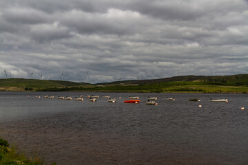 Rowing boats on lake or reservoir, wind turbines in background, copyspace.