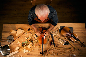 Senior carpenter craftsman carving wood and making violin instrument