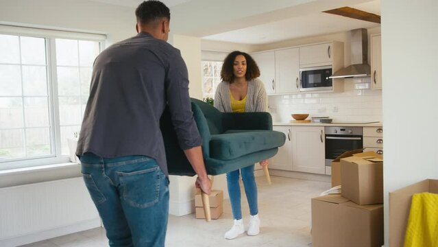 Couple carrying and sitting on sofa into new home on moving day - shot in slow motion