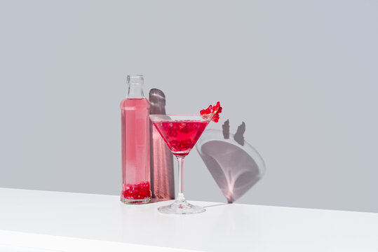 Pomegranate cocktail and bottle duo on gray background