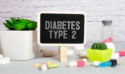 Ampoules, pills, stethoscope, thermometer, tablet with DIABETES TYPE 2 text on desktop.