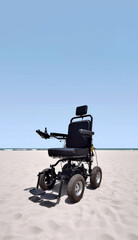 Empty black electric wheelchair parked on the beach in front of the ocean – free space for text