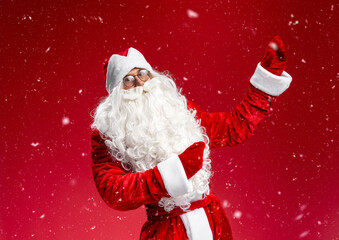 Happy Santa Claus dancing, having fun pointing hands on snow isolated on blue background. Christmas, winter holidays concept 