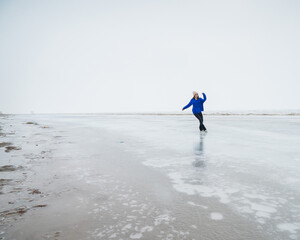 Caucasian woman in a blue sweater skating on a frozen lake. 