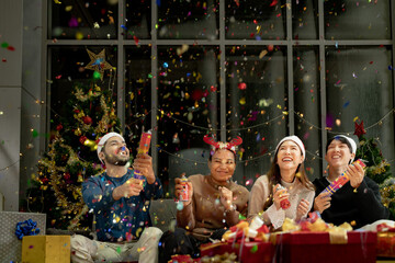 men and women using paper shoot in a party at living room. young couple Asian people enjoy celebrating Christmas and New Year. happy and celebrate with gift and presents.