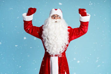 Portrait of funny excited Santa Claus holding hands up celebration Christmas isolated on blue background
