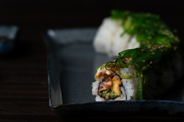 Salmon Sushi Roll with Wakame on top. Close-Up on Dark Mood Wooden Background
