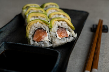 Sushi Delight. Close-Up of Salmon and Avocado Sushi Rolls with Soy Sauce and Chopsticks