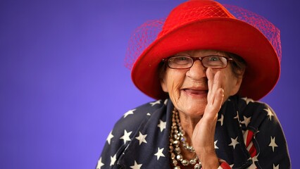 Closeup funny portrait of smiling happy crazy toothless grandmother with wrinkled skin puts hand to mouth to tell a secret wearing US flag jacket isolated on purple background studio