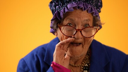 Closeup funny portrait of smiling happy crazy toothless grandmother with wrinkled skin puts hand to...
