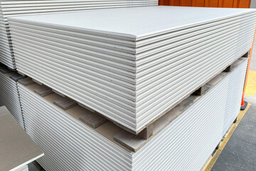 The stack of WHITE drywall Standard Gypsum board panel. Plasterboard. Panel Type A designed for indoor walls, partitions and ceilings, construction site