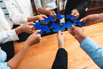 Multiethnic business people holding jigsaw pieces and merge them together as effective solution...
