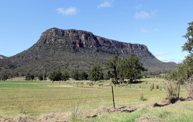Fototapeta na wymiar Mountain with trees, a field and a fence in the Capertee Valley in New South Wales, Australia