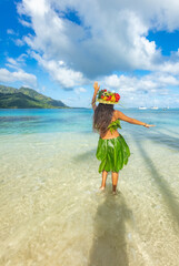 Jeune femme vahine dansant sur la plage en Polynésie en costumes traditionnel végétal