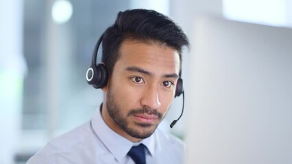 Call centre agent wearing headset giving great customer support service via email at his desk. Confident young sales representative making a sale at his helpdesk in the office.
