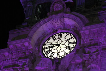 Estructura artesanal con un reloj estilo londres en su parte alta con colores morados reflejados en...