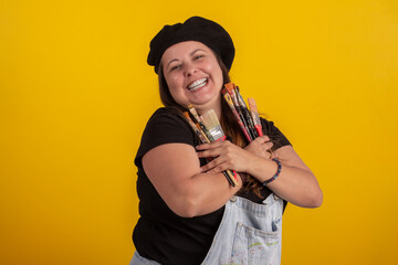 Plus size woman in stylish clothes in studio photos, with facial expressions and with paintbrushes in hand