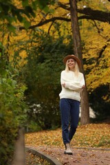 Happy woman wearing warm sweater walking in autumn park