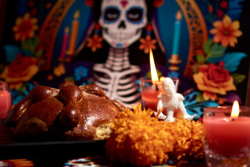 Bread of the dead with marigold flowers decorated with lit candles, in the background a catrina...