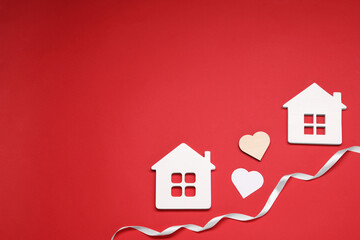 White ribbon and decorative hearts between two house models symbolizing connection in long-distance...