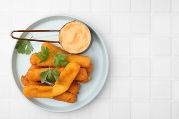 Tasty fried mozzarella sticks served with sauce and parsley on white tiled table, top view. Space for text