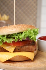 Delicious burger with tofu and fresh vegetables on wooden board, closeup