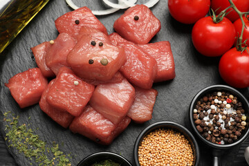 Raw beef meat and different ingredients for cooking delicious goulash on slate board, flat lay