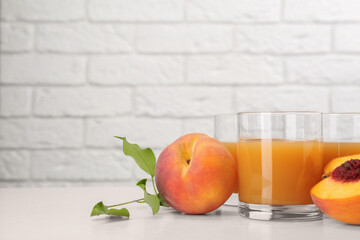 Glasses of delicious peach juice and fresh fruits on white wooden table. Space for text