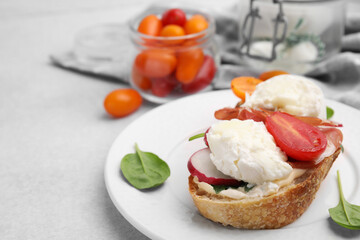 Delicious sandwich with burrata cheese, ham, radish and tomato on light grey table, closeup. Space for text