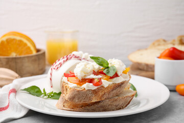 Delicious sandwich with burrata cheese and tomatoes on grey table, closeup. Space for text