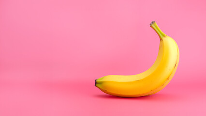A yellow banana against a pastel pink backdrop background with empty space for text, logo or quote...