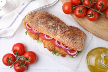 Delicious sandwich with schnitzel on white tiled table, flat lay