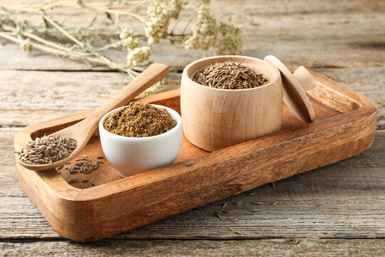 Caraway (Persian cumin) powder and dry seeds on wooden table, closeup