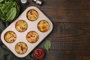 Freshly baked bacon and egg muffins with cheese in tin and tomato sauce on wooden table, flat lay....