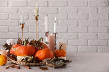 Composition with different pumpkins, burning candles and dry leaves on light marble table against...