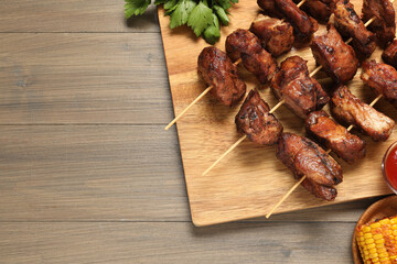 Delicious shish kebabs with vegetables on wooden table, flat lay. Space for text