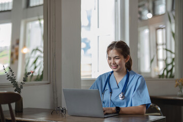 young asian lady doctor in white medical uniform with stethoscope using computer laptop talking video conference call with patient at desk in health clinic or hospital.