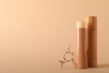 Lip balms on beige background, space for text