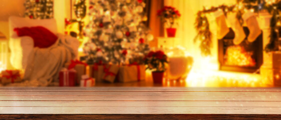 Empty wooden table in room with Christmas tree and fireplace. Banner with space for design