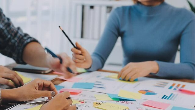 Two creative business people meeting and planning use post it notes sticky note on desk to share idea, Analysis data chart and graph with teamwork strategy brainstorming in office.