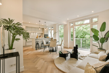 Naklejka premium a living room with wood flooring and white walls that are open to the kitchen, dining area and balcony