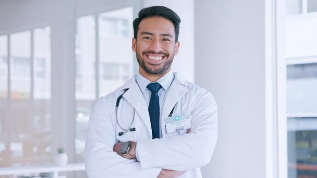 A confident male doctor is satisfied with the health of his patient. Portrait of a healthcare professional smiling with folded arms inside a hospital. A happy and proud GP standing in his office